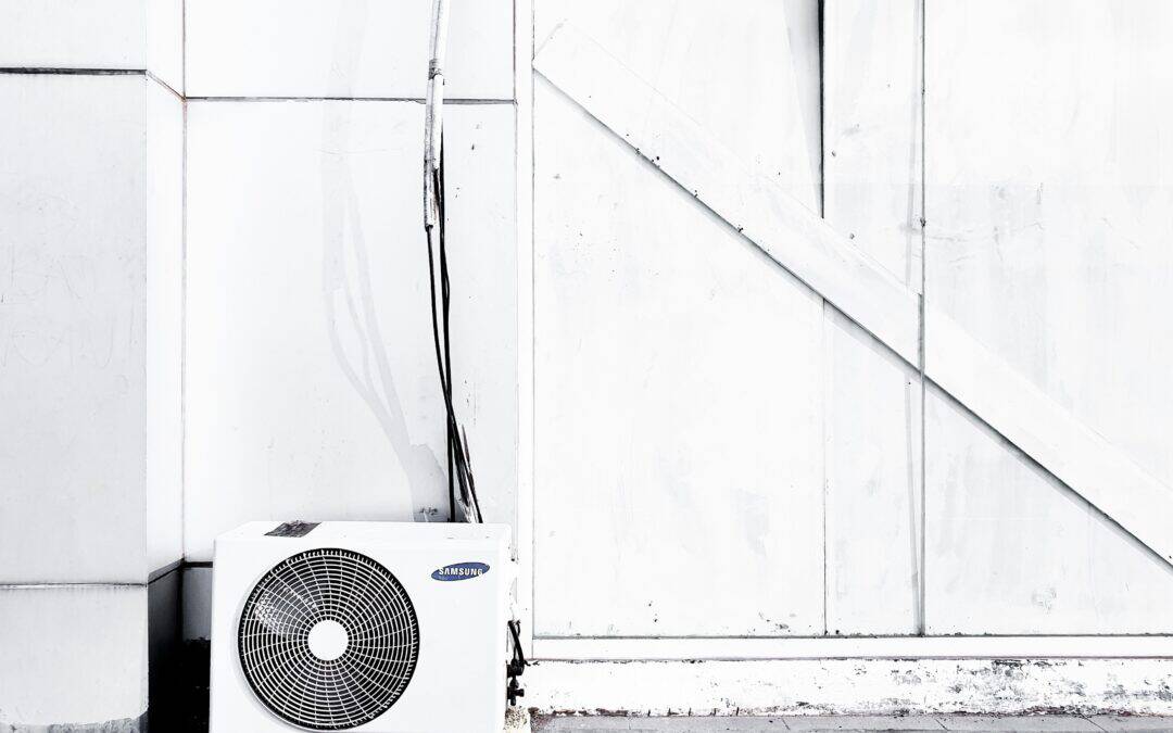 Ein Ventilator steht draußen vor einer weißen Wand.